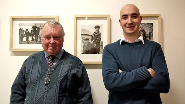 Gearóid Cheaist Ó Catháin, the last child to live on the Great Blasket Island with Dáithí de Mórdha, The Great Blasket Centre,  in front of a photograph of Gearóid with his Grandfather Maurice Mhuiris Ó Catháin, taken by Dan MacMonagle after the Island was evacuated in 1953.